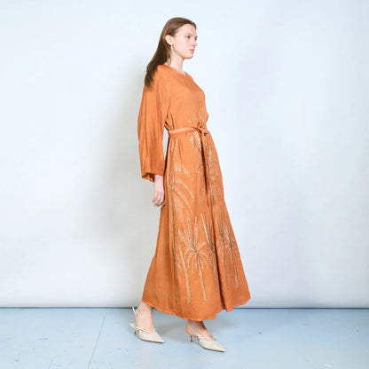 Abito lungo con maniche ampie, cintura e ricami decorativi